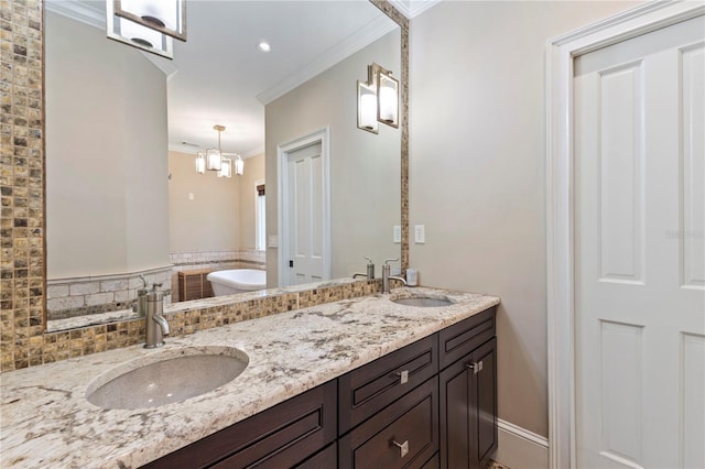 bathroom with an inviting chandelier, ornamental molding, a washtub, and vanity