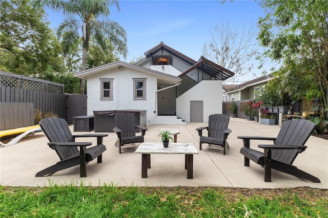 rear view of property featuring a hot tub and a patio