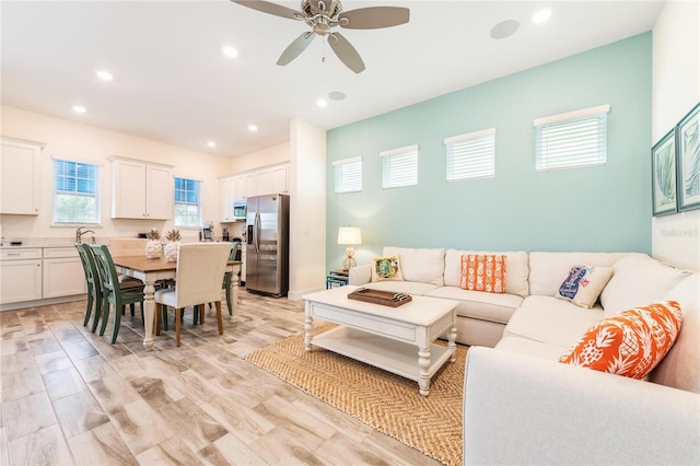 living room featuring ceiling fan, light hardwood / wood-style floors, a wealth of natural light, and sink