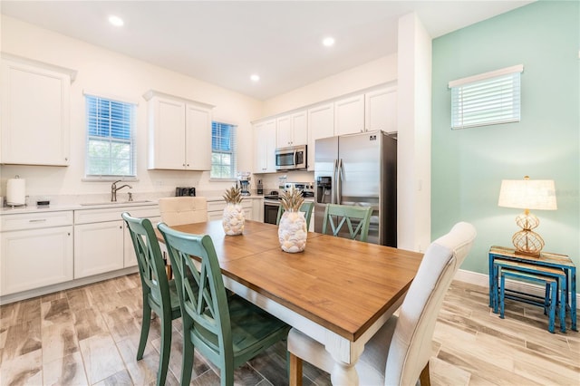 interior space with white cabinets, stainless steel appliances, light hardwood / wood-style flooring, and sink