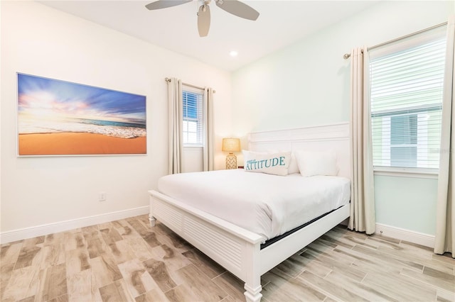 bedroom with ceiling fan, light hardwood / wood-style floors, and multiple windows