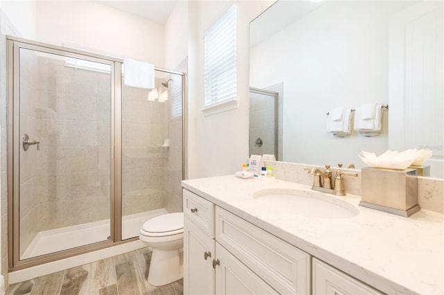 bathroom featuring toilet, an enclosed shower, vanity, and hardwood / wood-style floors