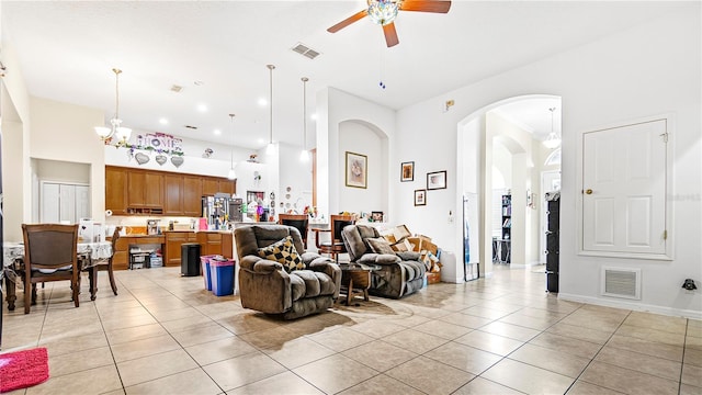 tiled living room featuring a high ceiling and ceiling fan with notable chandelier