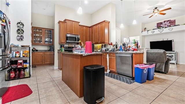 kitchen featuring light tile patterned floors, appliances with stainless steel finishes, pendant lighting, and a center island