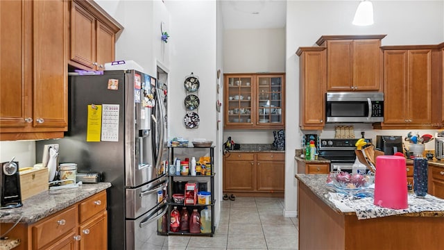 kitchen featuring light tile patterned flooring, stainless steel appliances, and light stone counters