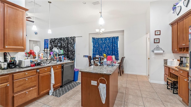 kitchen featuring decorative light fixtures, light stone countertops, a kitchen island, stainless steel dishwasher, and sink