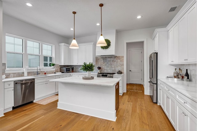 kitchen with appliances with stainless steel finishes, white cabinets, hanging light fixtures, and sink