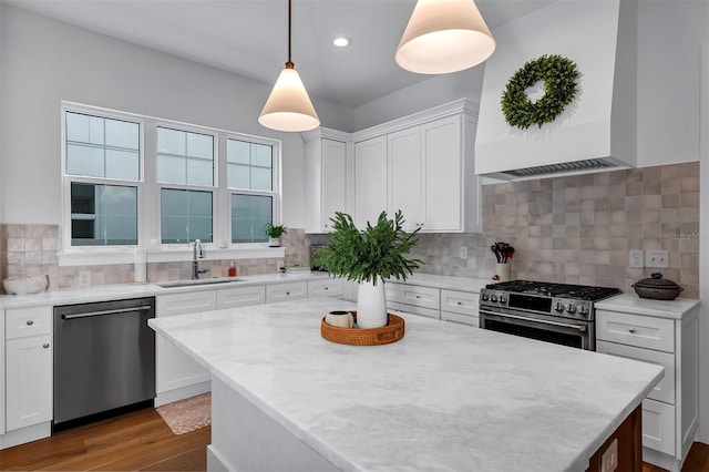 kitchen featuring white cabinetry, sink, hanging light fixtures, and appliances with stainless steel finishes