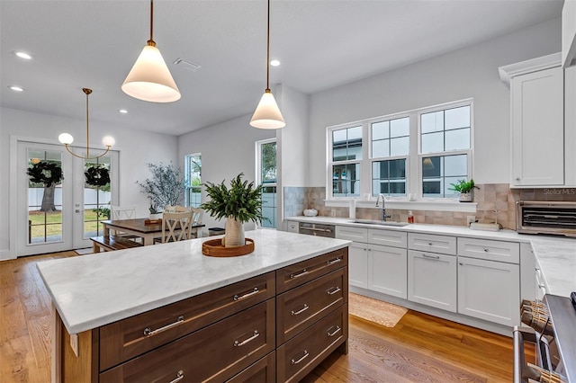 kitchen featuring white cabinets, backsplash, sink, and pendant lighting