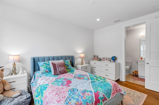 bedroom with wood-type flooring and connected bathroom