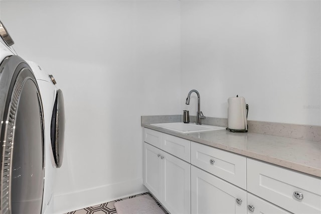 clothes washing area featuring light tile patterned floors, sink, and cabinets