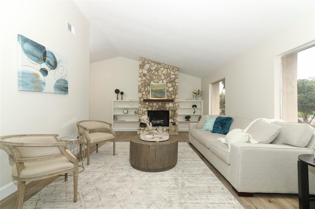 living room with lofted ceiling, a fireplace, and light hardwood / wood-style flooring