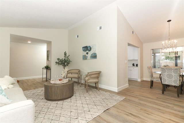 living room featuring light hardwood / wood-style floors, a notable chandelier, and lofted ceiling