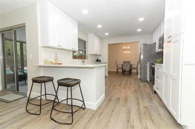 kitchen featuring kitchen peninsula, stainless steel appliances, and white cabinetry