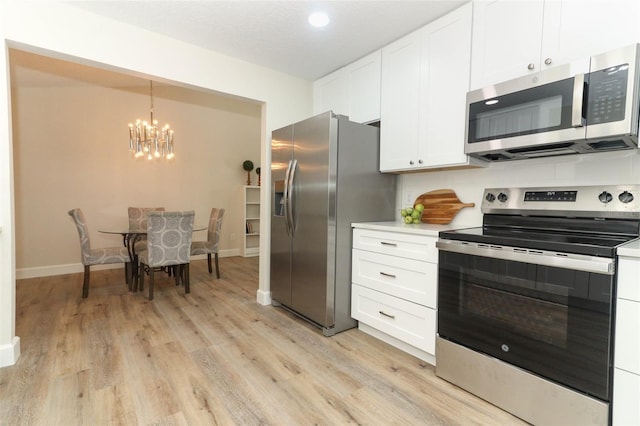 kitchen with white cabinets, an inviting chandelier, light hardwood / wood-style floors, hanging light fixtures, and appliances with stainless steel finishes