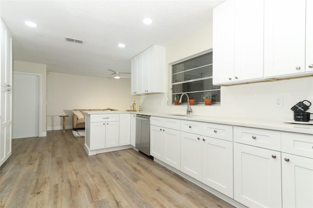 kitchen with kitchen peninsula, stainless steel dishwasher, light wood-type flooring, and white cabinetry