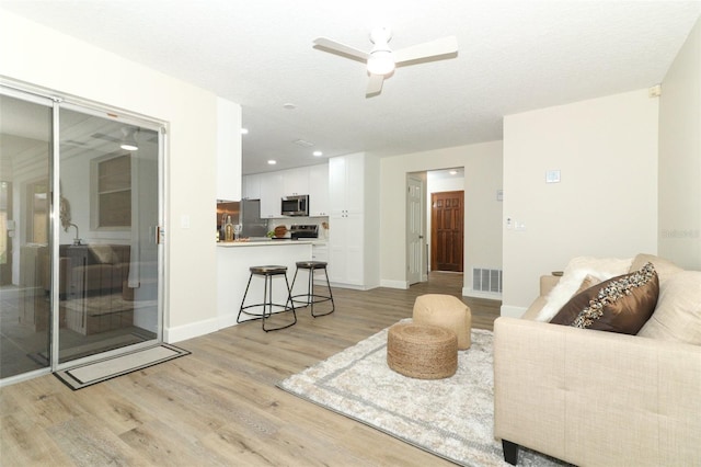 living room featuring ceiling fan and light hardwood / wood-style floors