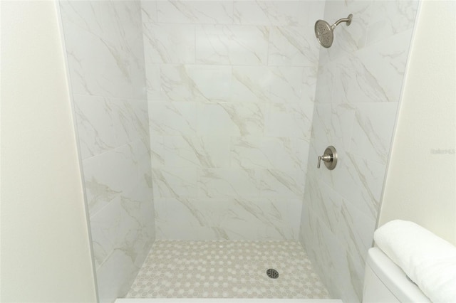 bathroom featuring toilet and a tile shower