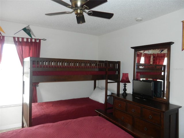 bedroom with ceiling fan and a textured ceiling