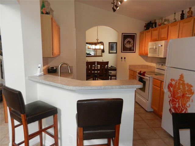 kitchen featuring white appliances, a breakfast bar, kitchen peninsula, and hanging light fixtures