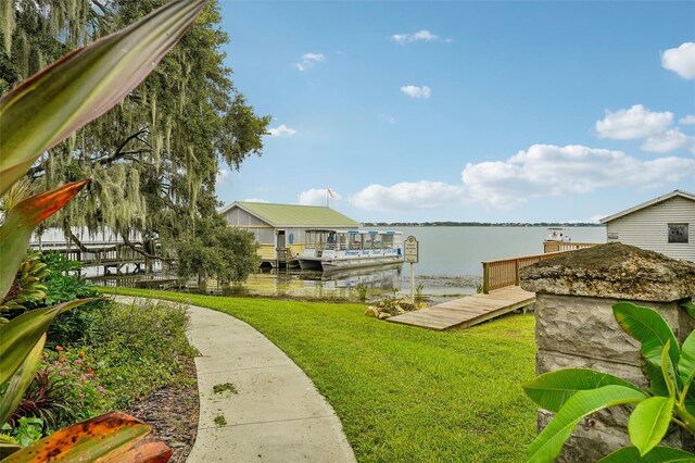 view of dock with a yard and a water view