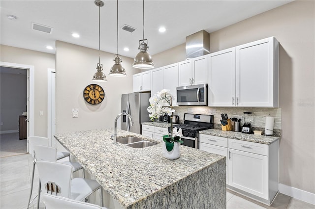 kitchen with sink, stainless steel appliances, white cabinetry, and an island with sink