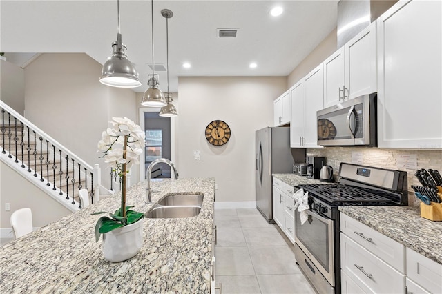 kitchen featuring sink, light stone countertops, white cabinets, and appliances with stainless steel finishes