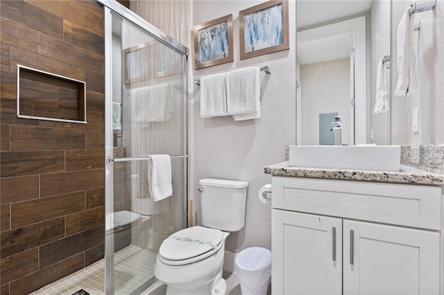 bathroom featuring toilet, a shower with shower door, and vanity