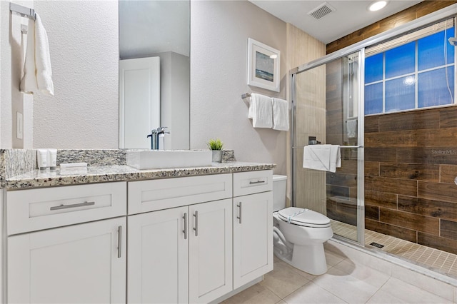 bathroom with a shower with shower door, toilet, vanity, and tile patterned flooring