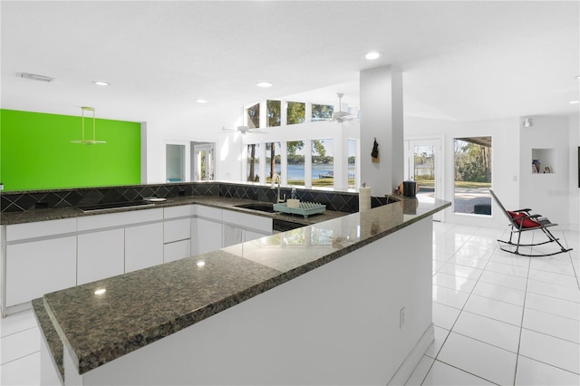 kitchen featuring sink, white cabinetry, dark stone countertops, ceiling fan, and light tile patterned floors