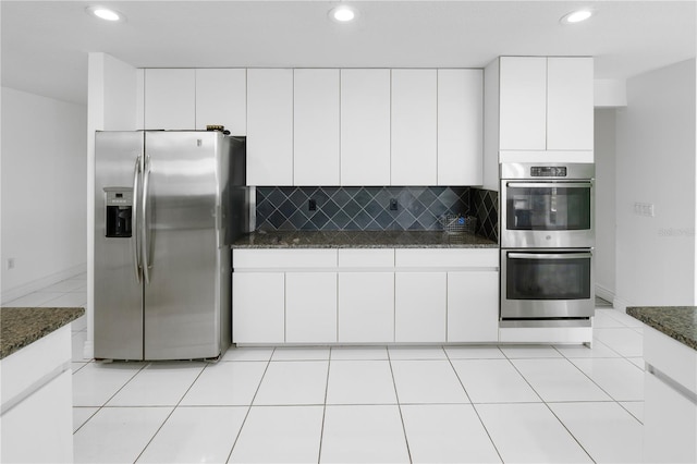 kitchen with appliances with stainless steel finishes, dark stone countertops, tasteful backsplash, and white cabinetry