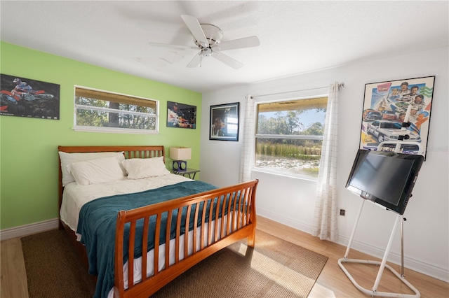 bedroom with hardwood / wood-style flooring, ceiling fan, and multiple windows