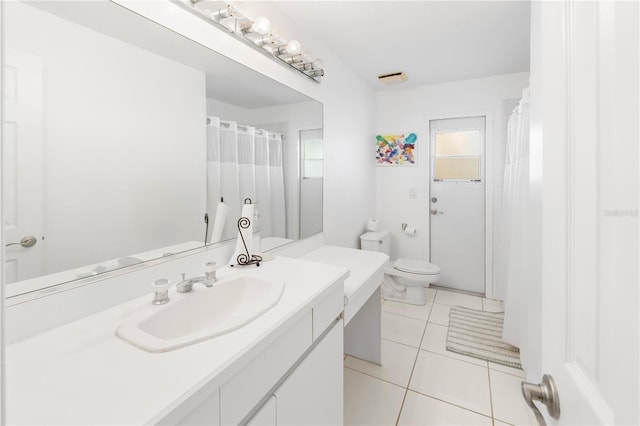 bathroom featuring toilet, vanity, tile patterned floors, and a healthy amount of sunlight