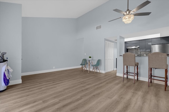 living room featuring high vaulted ceiling, ceiling fan, and light hardwood / wood-style floors