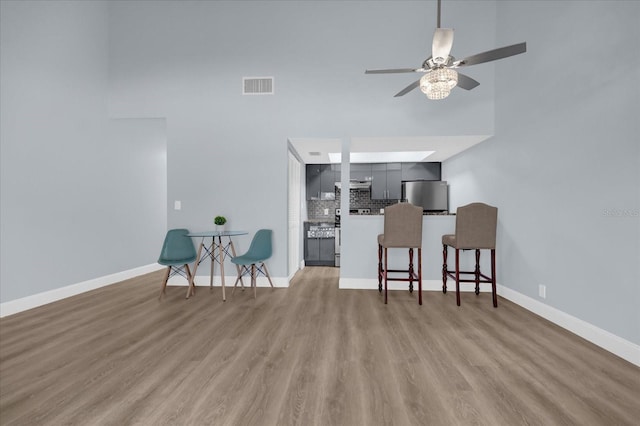 living room featuring a towering ceiling, wood-type flooring, and ceiling fan