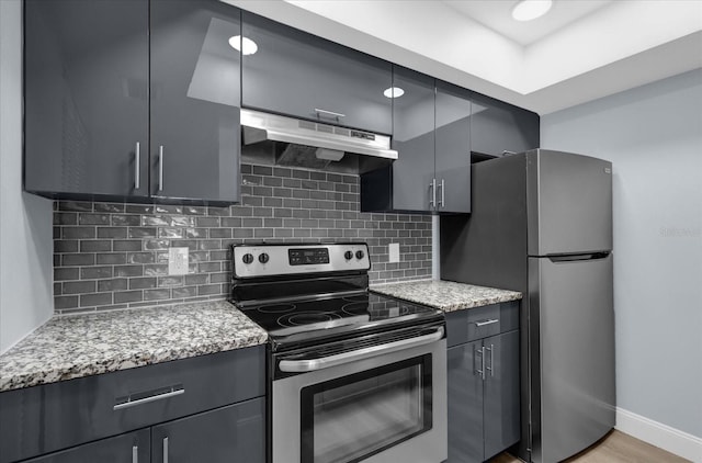 kitchen featuring stainless steel appliances, light hardwood / wood-style floors, tasteful backsplash, and light stone counters