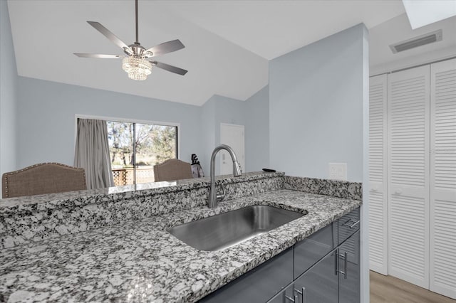 kitchen featuring sink, lofted ceiling, ceiling fan, light stone countertops, and dark hardwood / wood-style floors