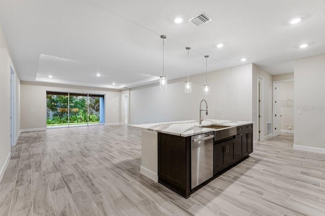 kitchen featuring sink, a tray ceiling, dishwasher, an island with sink, and pendant lighting