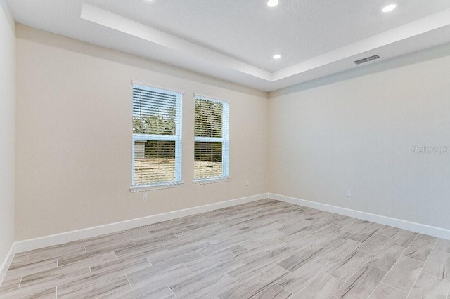 unfurnished room with light hardwood / wood-style floors and a raised ceiling