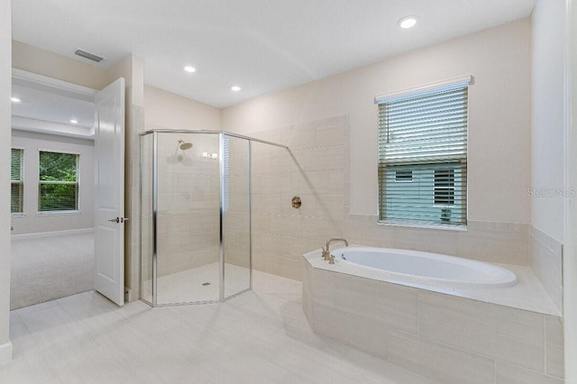 bathroom with a wealth of natural light and shower with separate bathtub