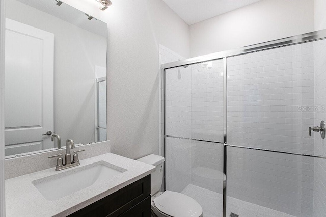 bathroom featuring vanity, walk in shower, and toilet