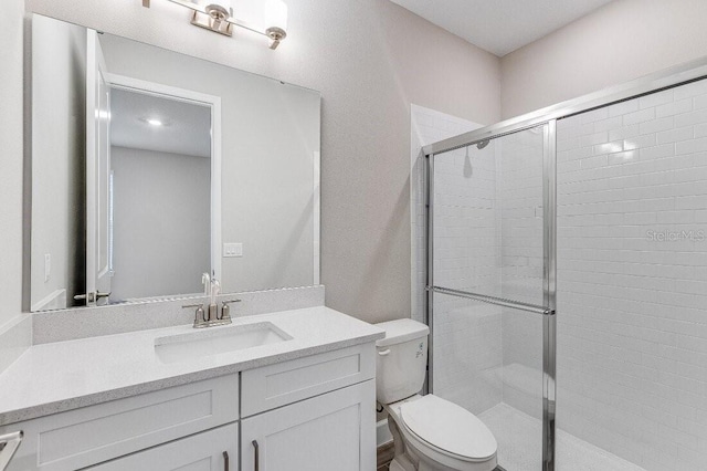 bathroom with walk in shower, vanity, and toilet