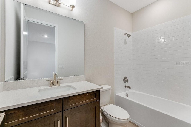 full bathroom featuring vanity, tiled shower / bath, and toilet