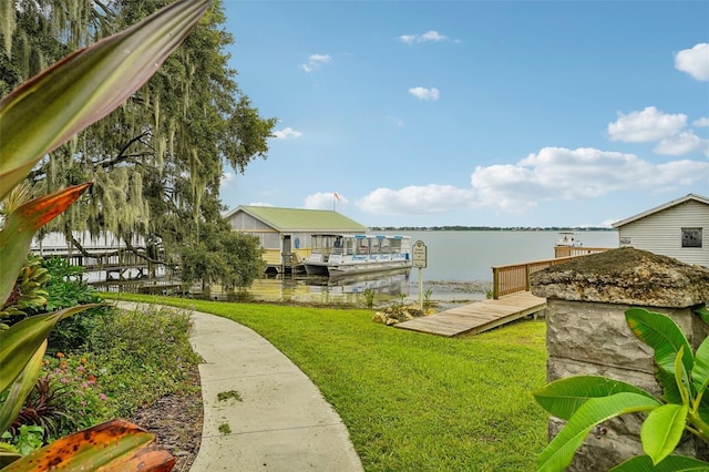 view of dock with a yard and a water view