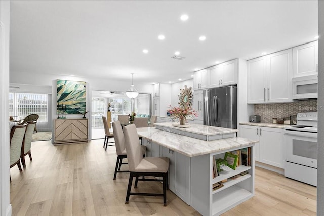 kitchen featuring white appliances, white cabinetry, hanging light fixtures, tasteful backsplash, and a kitchen island