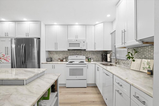 kitchen featuring white cabinetry, sink, light stone counters, and white appliances