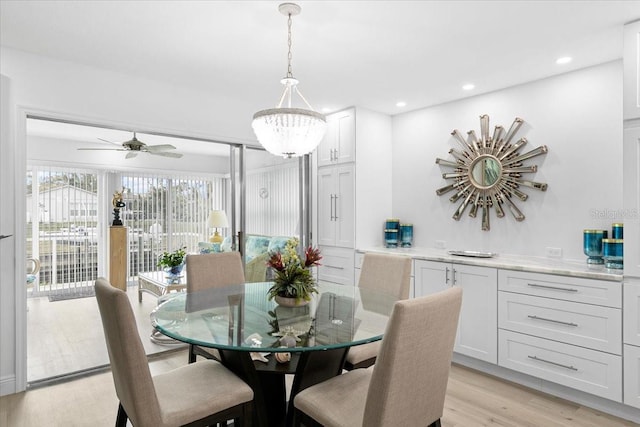 dining room with ceiling fan with notable chandelier and light hardwood / wood-style flooring