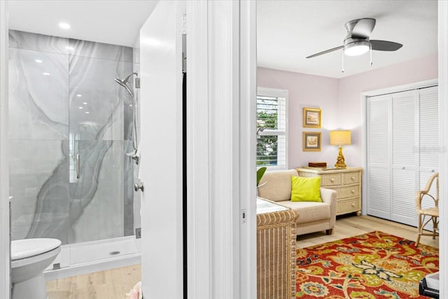 bathroom featuring hardwood / wood-style flooring, toilet, ceiling fan, and a shower with shower door