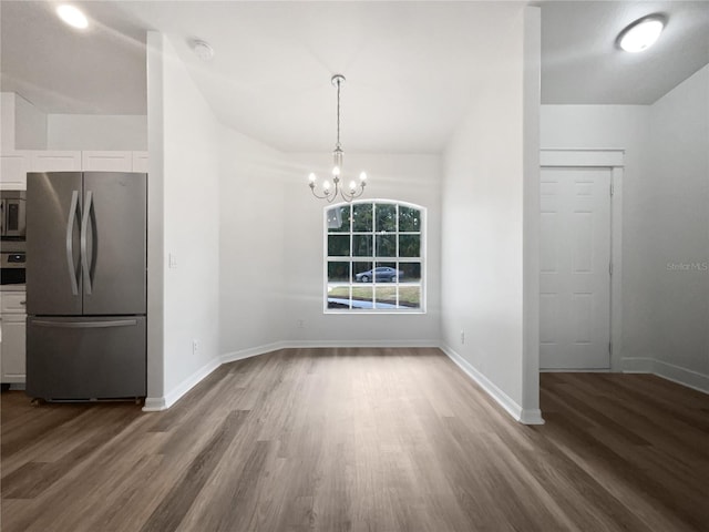 unfurnished dining area with an inviting chandelier and hardwood / wood-style floors