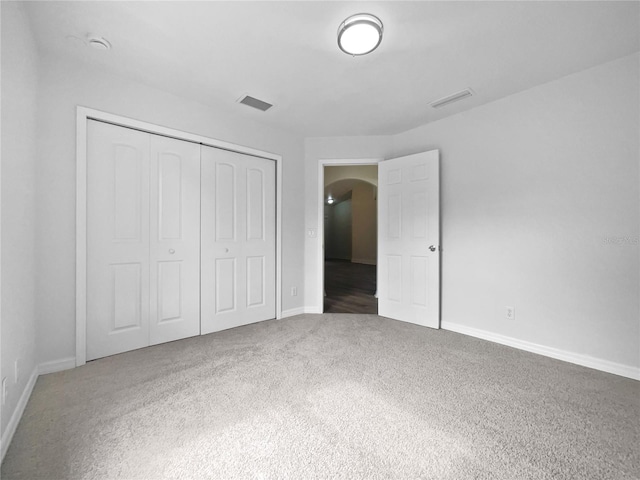 unfurnished bedroom with dark colored carpet and a closet